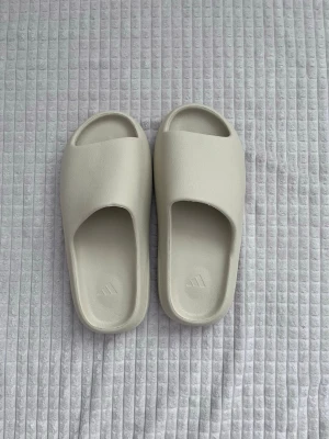 Yeazy slides Tofflor - Väldigt snygga adidas yeazy slides tofflor i beige färg, helt oanvända och dem säljs pga att jag inte behöver dem. 