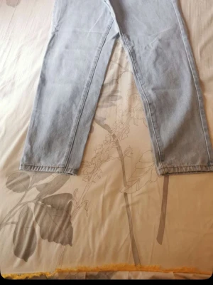Ljusblå raka jeans - Säljer ett par ljusblå jeans med rak passform och klassisk femficksdesign. Jeansen har hög midja och är tillverkade i ett mjukt denimtyg. Perfekta för en avslappnad och trendig look.