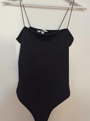 Svart body med tunna axelband H&M - En svart body från H&M med tunna axelband och stilren design som passar många tillfällen, alltifrån fest till vardag. I storlek S. Materialet är mjukt och stretchigt och den har även dubbeltyg❤️