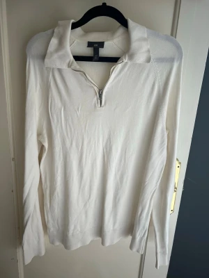 Vit långärmad tröja med dragkedja H&M - Snygg vit långärmad tröja från H&M med halv dragkedja framtill och bred krage. Tröjan har en clean look och är tillverkad i mjukt material som passar perfekt till många olika outfits.