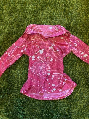 Rosa mönstrad meshblus med krage - Letar hem till en rosa meshblus med vitt abstrakt mönster och glittriga detaljer. Blusen har en bred krage, knapp framtill och långa ärmar. Materialet är tunt, och perfekt för att skapa en cool lager-på-lager-look. Står 42 på lappen, men är snarare 38.