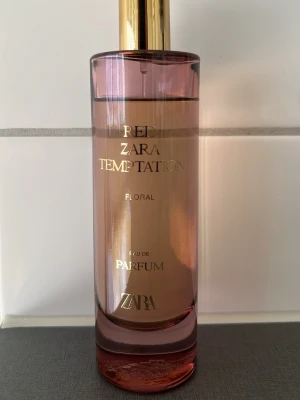 Zara Red Temptation Floral Parfym - Zara Red Temptation Floral är en elegant parfym i en cylinderformad glasflaska med rosa ton och guldfärgad kork. Doften är blommig och flaskan har stilrena guldfärgade detaljer. Perfekt för dig som gillar fräscha och feminina dofter.