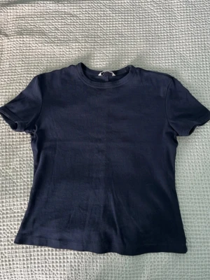 Zara Mörkblå basic t-shirt - En enkel mörkblå t-shirt med rund hals och korta ärmar. Perfekt till jeans eller shorts för en clean och avslappnad look. Tillverkad i mjuk bomull som känns skön mot huden.
