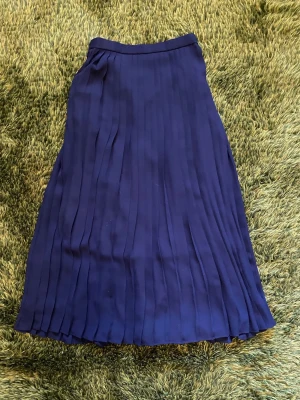 Mörkblå plisserad maxi skirt - Snygg mörkblå plisserad långkjol med hög midja och flowig passform. Kjolen har ett klassiskt och stilrent utseende som passar perfekt till många olika looks. Materialet känns lätt och bekvämt och passar bra till sommaren.