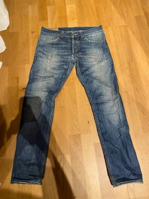 Dondup jeans - Säljer ett par blå Dondup jeans med snyggt slitna detaljer och raka ben. Jeansen har klassisk femficksdesign och kontrastsömmar. Perfekta för en avslappnad och trendig look. Inte säker på storlek men skulle gissa 31 eller 32. Finns ett hål mellan benen se bild 4
