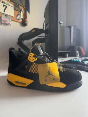 Air Jordan 4 Retro - Säljer ett par Air Jordan 4 Retro sneakers i svart och gult. Skorna har meshpaneler, plastdetaljer och synlig Air-dämpning i sulan. Klassisk Jumpman-logga på tungan och tag. Perfekt för dig som vill sticka ut med en ikonisk modell. De är äkta också 
