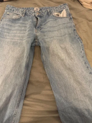 Ljusblå raka jeans från 157 - Säljer ett par ljusblå jeans från 157 med klassisk femficksmodell och raka ben. Jeansen har bälteshällor och dragkedjegylf. Perfekta för en avslappnad och trendig look.