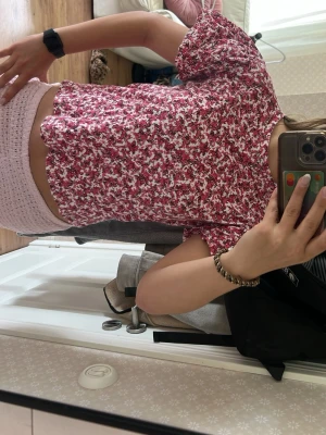 Blommig rosa blus med puffärm - Supersöt blommig blus från Zara i rosa och vitt med korta puffärmar och avslappnad passform. Perfekt till jeans eller kjol för en trendig look. Blusen har små volangdetaljer vid ärmslut och är tillverkad i ett lätt och luftigt material.