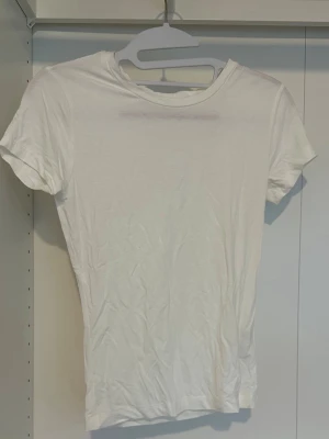 Vit basic t-shirt  - En enkel vit t-shirt med rund hals och korta ärmar.  Perfekt att styla lager på lager eller bära som den är.