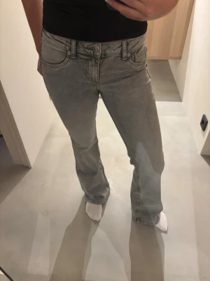 Grå bootcut jeans med låg midja - Säljer ett par gråa bootcut jeans med låg midja och klassisk femficksdesign. Jeansen har en snygg tvättad look och raka ben som går ut lite nedtill🌸