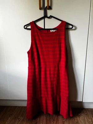 Klänning från LOFT - Snygg (korall) röd klänning från LOFT med ärmlös design och rund halsringning. Klänningen har ett diskret hålmönster och lätt utställd kjol. Perfekt för dig som vill ha en enkel men ändå iögonfallande look. I fint använt skick.