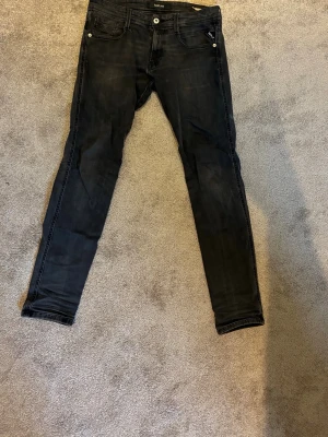 Gråa slim fit jeans från Replay - Säljer ett par gråa  slim fit jeans från Replay med klassisk femficksdesign och diskreta slitningar. Stretchigt material för extra komfort. 