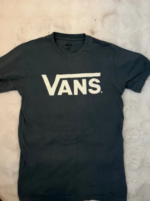 Svart Vans t-shirt med logga - Mörkblå t-shirt från Vans i storlek XS med stor vit Vans-logga på bröstet. Klassisk rund halsringning och korta ärmar. Använd flertalet gånger.