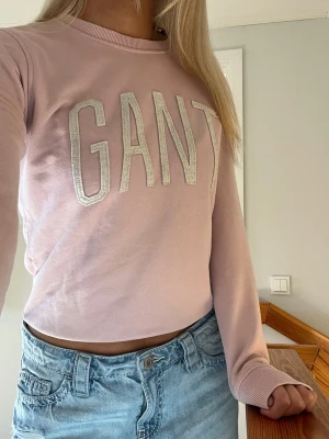 Ljusrosa sweatshirt från GANT - Ljusrosa sweatshirt från GANT med stora vita bokstäver. Tröjan har rund halsringning, långa ärmar och ribbade muddar vid ärmslut och nederkant. Perfekt för en färgglad och gullig outfit💗💗