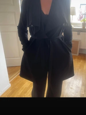 Svart trenchcoat med knytskärp -  svart trenchcoat med knytskärp i midjan.