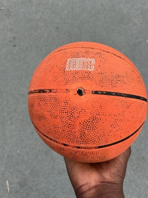 Orange basketboll med svarta linjer - Klassisk orange basketboll med svarta linjer, perfekt för spel på utomhusplan. Tillverkad i slitstarkt gummimaterial som ger bra grepp och studs. Passar både träning och spontanspel med vänner.