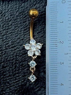 NY oanvänd Navelpiercing med hänge | Kirurgiskt stål | Blomma och vita stenar  - 💕30% Bundle-rabatt vid köp av minst 2 artiklar. ⭐️NY oanvänd piercing i kirurgiskt stål; rostfritt och säkert för läkta piercingar.                               📏MÅTT ⭕️Stavens längd: 10mm ⭕️Stavens tjocklek: 1,6mm ⭕️Smyckets totala längd: 35mm                                                                         🤍Färger: Guld och vit                                                           💌Skickas spårbart via Plick SafePay.