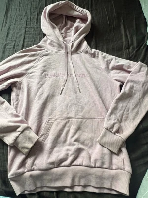 Rosa hoodie från Peak Performance - Säljer en rosa hoodie från Peak Performance med broderad logga på bröstet. Hoodien har stor huva med dragsko, magficka och ribbade muddar vid ärmar och nederkant. Perfekt för en chill och avslappnad stil.