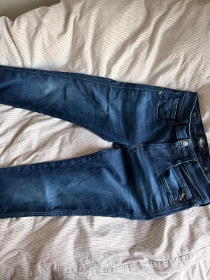 Mörkblå skinny jeans från Only - Säljer ett par mörkblå skinny jeans från replay med klassisk femficksdesign och normalhög midja. Jeansen har stretchigt material för skön passform och silverfärgade detaljer vid knappar och nitar. Perfekta till en avslappnad och trendig look. 