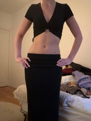 Svart långkjol i stretchigt material - Säljer en svart långkjol med rak passform och hög midja. Kjolen är enkel och stilren, perfekt att matcha med crop tops eller stickade tröjor. Materialet känns stretchigt och följsamt, vilket gör den bekväm att bära hela dagen.