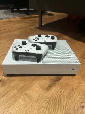 Xbox One S med två vita handkontroller - Xbox One S säljes i bra skick!  Säljer mitt Xbox One S som fungerar perfekt. Konsolen är väl omhändertagen och i bra skick. Två handkontroller ingår, båda fungerar som de ska.  Perfekt för dig som vill spela populära spel, streama filmer eller ha en prisvärd spelkonsol.  ✓ Xbox One S ✓ 2 handkontroller ✓ Bra skick ✓ Fungerar utan problem  Hör av dig vid intresse eller om du har några frågor!