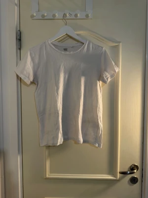 Två vita t-shirts, en med v-ringning - Säljer två vita t-shirts i enkel och stilren design. Ena t-shirten har klassisk rund hals och normal passform, medan den andra har djup v-ringning och sitter lite tightare. Perfekta basplagg till garderoben.