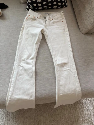 Vita bootcut jeans från junkyard - Säljer ett par vita bootcut jeans från junkyard med klassisk femficksmodell och snygga detaljer i metall. Jeansen har en något utsvängd passform nedtill och är tillverkade i ett mjukt bomullsmaterial. Precis nya. 