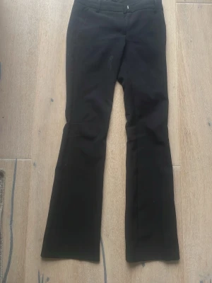 Svarta utsvängda kostymbyxor - Snygga svarta kostymbyxor med utsvängda ben och klassisk midja. Byxorna har en stilren look med diskreta fickor fram och är perfekta för en trendig och clean outfit. Materialet ser ut att vara mjukt och följsamt, vilket ger en bekväm passform. Ska tvättas och PRIS KAN DISKUTERAS‼️