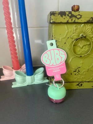 BUBS Watermelon Läppbalsam - Sött läppbalsam från BUBS by H&M i en rund mintgrön och rosa förpackning. Doft av vattenmelon och smidig att ha med sig tack vare nyckelringsfästet. Perfekt för dig som vill ha mjuka läppar med en fräsch doft. Slutsålt i hela landet. 