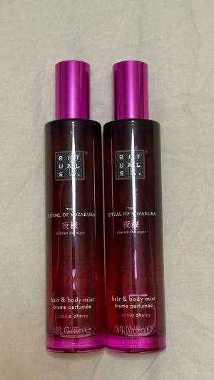 Rituals The Ritual of Yozakura Mist - Helt nya och oanvända!! Två flaskor Rituals The Ritual of Yozakura hair & body mist med doft av yoshino cherry. Flaskorna är cylinderformade i mörklila glas med metallicrosa lock och har en elegant, modern design. Perfekt för dig som vill ha en fräsch och blommig doft.