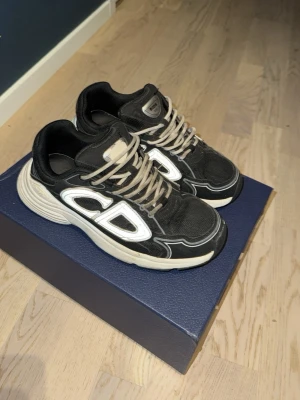 B30 - Snygga sneakers med chunky vit sula och stora. Skorna har mesh och läderpaneler, samt beige och svarta snören. Perfekta för dig som gillar statement sneakers och streetwear vibes.