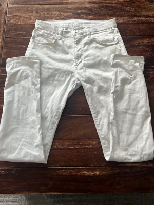 Vita tunnare slim fit jeans från Uniqlo - Snygga vita slim fit jeans från Uniqlo med klassisk femficksdesign. Jeansen är tillverkade i en bomullsblandning med stretch för extra komfort. Perfekta för en fräsch och stilren look.
