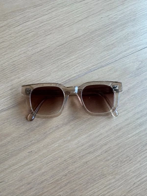 Solglasögon från Chimi - Snygga solglasögon med transparent beige båge och fyrkantig form. Glasen är bruna med en lätt toning som ger en cool vibe. Perfekta för att lyfta din stil under soliga dagar. Använda ett par säsonger. Kan finnas någon repa i glaset, men inget som påverkat när jag använt dem. Har justerats hos Chimi och får säkert att göra igen. 