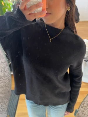 Svart stickad tröja med rund hals - En stilren svart stickad tröja med rund hals och långa ärmar. Tröjan har en enkel och klassisk design som passar till mycket. Mjuk och bekväm, perfekt för lager-på-lager. Snygg till både jeans och kjol.