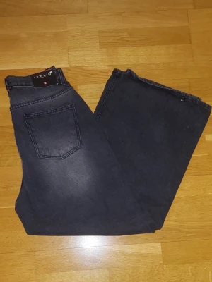Svarta wide leg jeans från Lewkin - Säljer ett par svarta wide leg jeans från Lewkin. Jeansen har hög midja, en snygg tvättad look med ljusare partier framtill. streetwear-stil.
