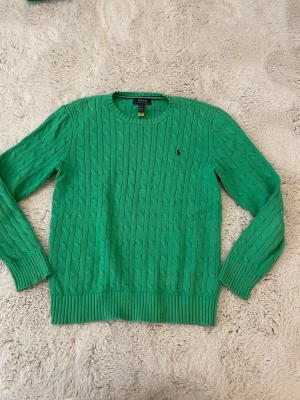 Grön kabelstickad tröja  Ralph Lauren - Tjena säljer denna gröna kabelstickade Ralph Lauren tröja. Barnstorlek L passar som vuxenstorlek XS.