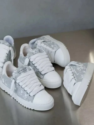 Himmel gråa sneaakers from Numeris  - Snygga sneakers från NUMERIS i grått och vitt med vita snören och kontrastsömmar. Ovandelen är i slätt och texturerat syntetmaterial, och sulan är vit med räfflad kant. Klassisk låg modell som passar till många stilar. Storlek 42, kom gärna med prisförslag. Skorna har använts vid få tillfällen och det syns