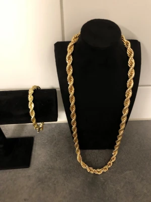 Guldfärgat tvinnat halsband - Säljer ett snyggt guldfärgat halsband med tvinnad design. Halsbandet har en chunky och glansig look som verkligen sticker ut. Perfekt för dig som gillar statement-smycken och vill addera lite extra bling till din stil.