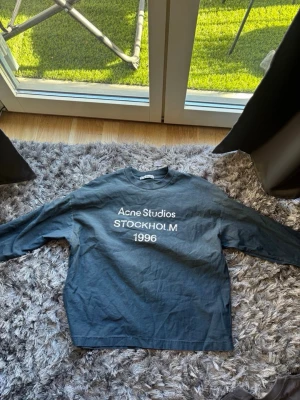 Svart sweatshirt Acne Studios strl S  - Cool svart sweatshirt från Acne Studios med vit text 'STOCKHOLM 1996' på bröstet. Oversized passform och rund halsringning. Perfekt för en avslappnad streetstyle-look.   