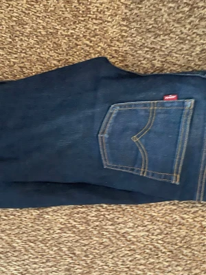 Levi's 512 Slim Taper mörkblå jeans - Snygga mörkblå Levi's 512 Slim Taper jeans med klassisk femficksdesign och kontrastsömmar. Jeansen har en smal passform som smalnar av nedtill och är tillverkade i slitstarkt denim. Perfekta för dig som gillar en modern och stilren look.