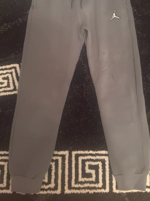 Grått Jordan set med hoodie och byxor - Säljer ett grått set från Jordan med hoodie och matchande byxor. Hoodien har dragsko och stor ficka framtill, byxorna har resår vid benslut. Båda delar har den klassiska Jumpman-loggan på bröstet och höften. Perfekt för en avslappnad och sportig look.