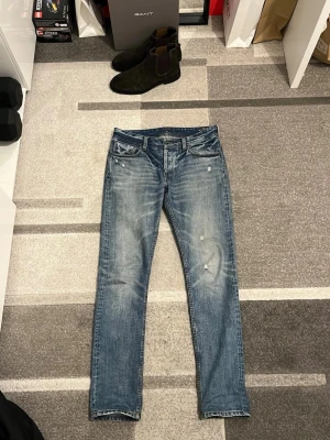 Blå selvedge jeans från NN07 - Säljer ett par snygga blå jeans från NN07 med snygga fades och slitningar. Jeansen har en femficks design, normal passform och raka ben, selvedge. Jeansen har en cool vintagekänsla med små slitningar 