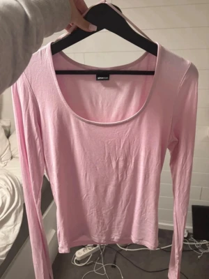 Ljusrosa långärmad topp Gina Tricot - En enkel och stilren ljusrosa långärmad topp från Gina Tricot. Toppen har en rund, djup urringning och är gjord i mjuk bomullsmix. Perfekt att matcha med jeans eller kjol för en clean look.