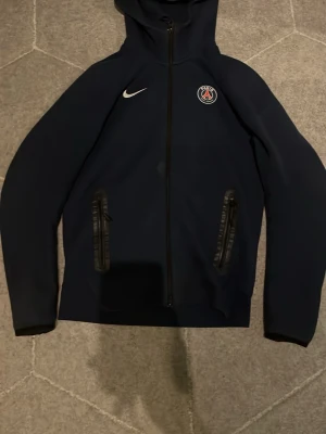 Nike tech PSG - Nike tech PSG mörkblå. Skön och varm! Den är i bra skick lite syn av användning. Köpt på JD Sport. Kontakta vid intresse! 