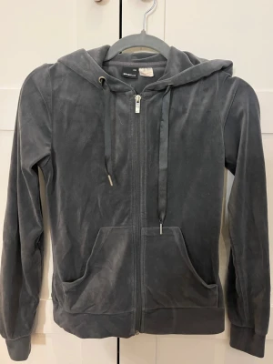 Grå tröja från ginatricot - Mjuk och skön mörkgrå tröja från ginatricot. Tröjan har dragkedja framtill, två stora fickor och justerbar huva med snören. Perfekt för en avslappnad och trendig look. Använd men bra skick. Kan gå ner lite i pris vid seriöst intresse. 