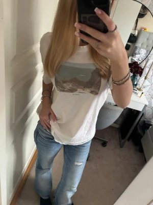 Vit t-shirt från Gina - Vit t-shirt med ett tryck av ett strandmotiv på bröstet. T-shirten har rund halsringning och korta ärmar. Passformen är normal och materialet känns som mjuk bomull. Perfekt för en avslappnad och stil. Jag köpte den i M för jag älskade oversized innan så den är pösigare på mig🥰