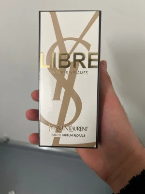 Yves Saint Laurent Libre Flowers & Flames - Yves Saint Laurent Libre Flowers & Flames Eau de Parfum Florale i 90 ml. Lyxig parfym i elegant och vit och guld förpackning med stor YSL-logga. Doften är blommig och modern, perfekt för dig som vill ha något fräscht och exklusivt.