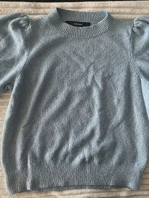 Ljusblå puffärm stickad tröja Vero Moda - Säljer en ljusblå stickad tröja från Vero Moda med puffärmar och ribbade muddar vid hals, ärmslut och nederkant. Tröjan har en mjuk och mysig känsla, rund halsringning och kortare ärmar med volym.💕Inga synliga defekter, varsamt använd🤗