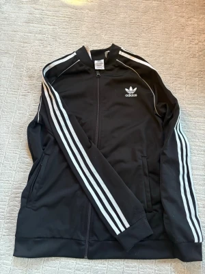 Adidas kofta - Klassisk svart Adidas track jacket med vita ränder i storlek S.