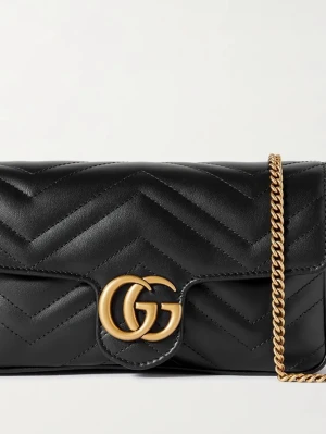 Svart kuvertväska från Gucci - Snygg svart kuvertväska från Gucci i quiltat läder med guldfärgad kedja och GG-logga framtill. Väskan har en elegant, rektangulär form och klassisk design som gör den till ett statement-piece. Perfekt för dig som gillar lyxiga detaljer och trendig stil.